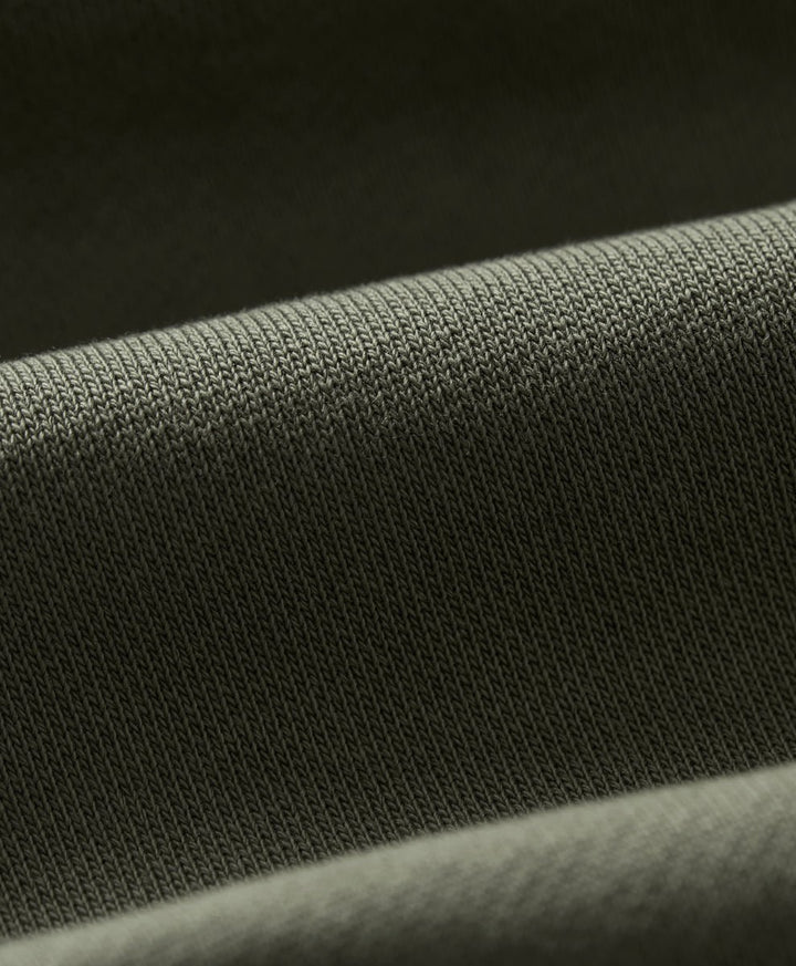Close-up of a dusted green knit fabric texture with soft folds.