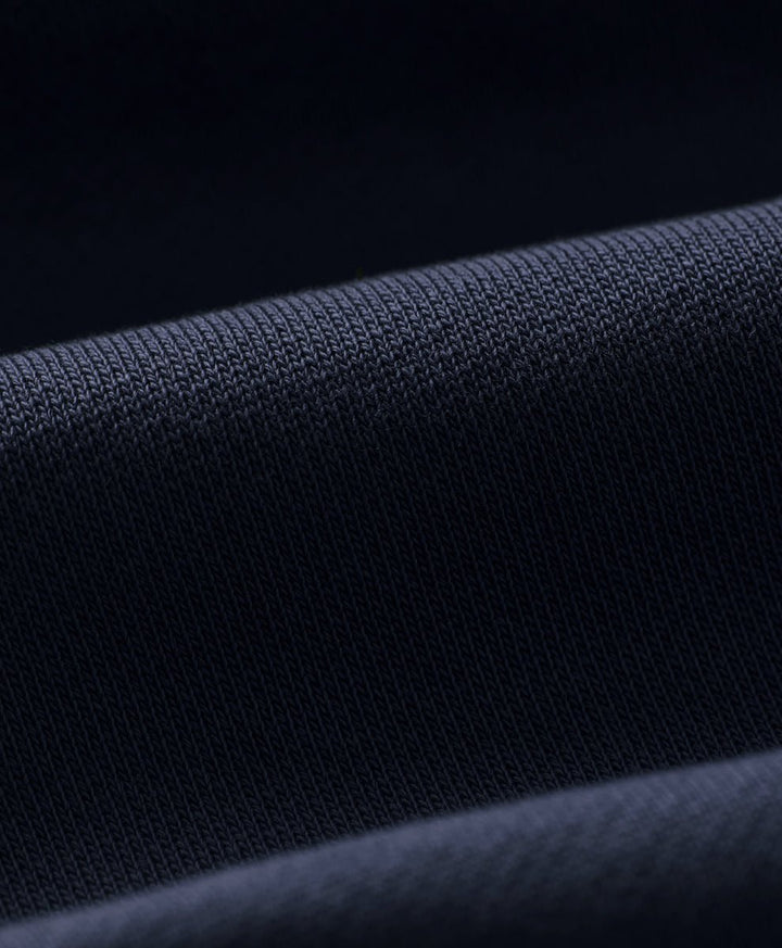 Close-up of dark navy blue knit fabric with a fine ribbed texture and soft folds.