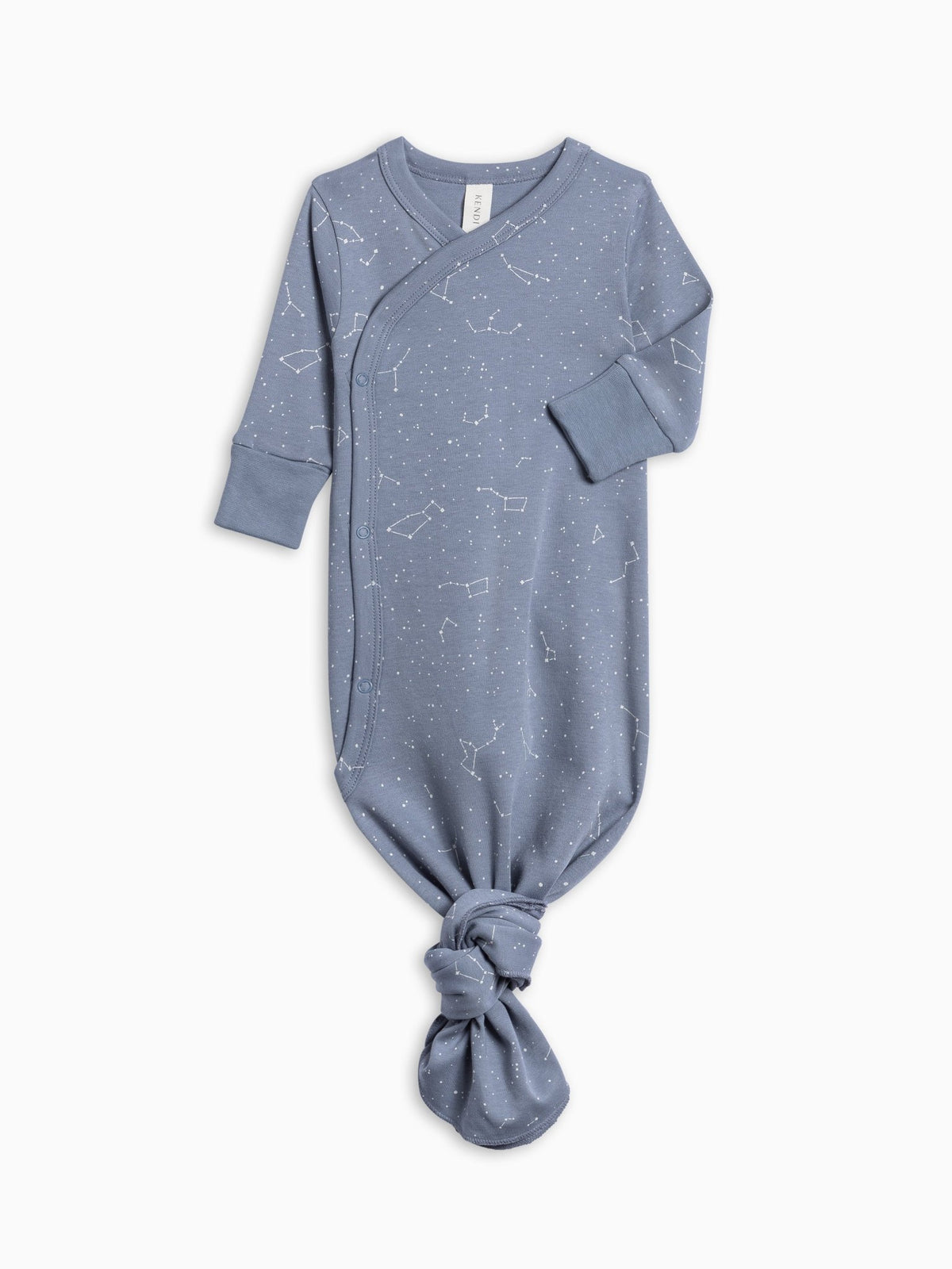 A baby long-sleeve footless sleeper in dusty blue with a white constellation print, featuring a wrap-style neckline and a knotted leg detail, shown on a plain white background.