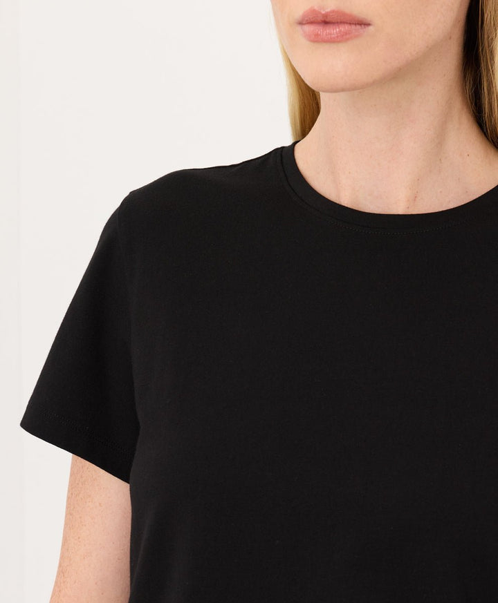 Woman wearing a Pact black Organic Luxe Essential Crewneck Tee against a plain background.
