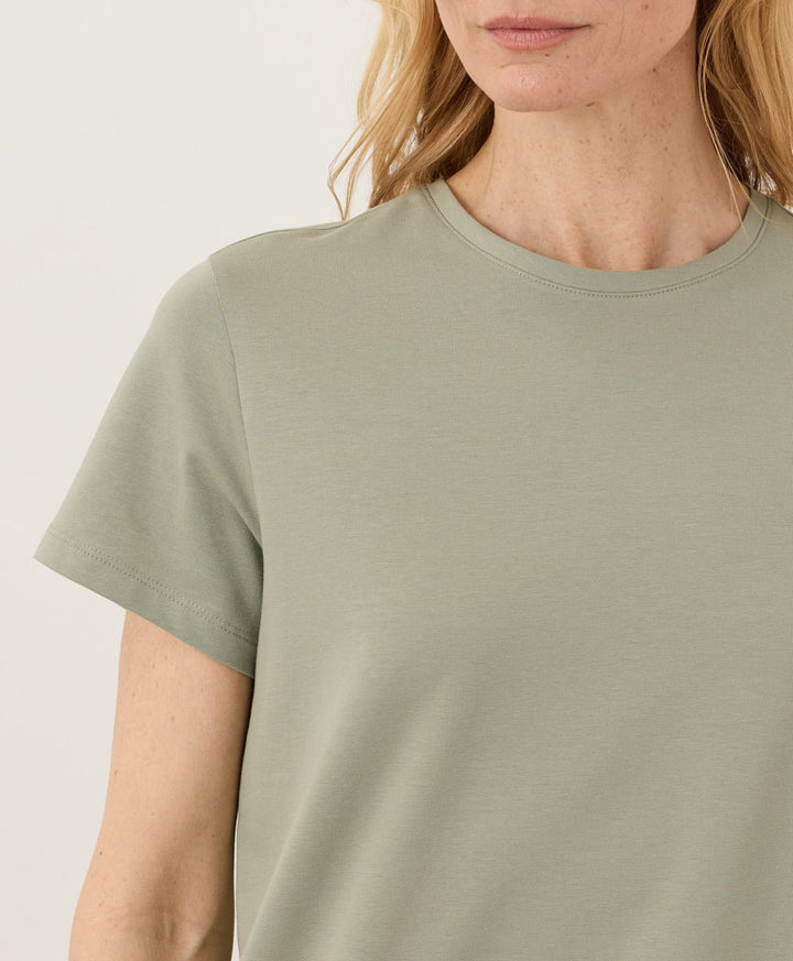 Woman wearing a Pact seagrass Organic Luxe Essential Crewneck Tee against a plain background