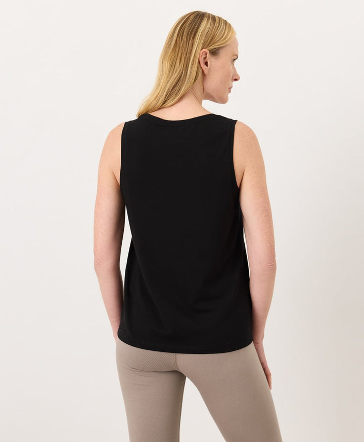 Woman wearing a black Pact Organic Luxe Essential Scoop Neck Tank and cinder leggings against a white background
