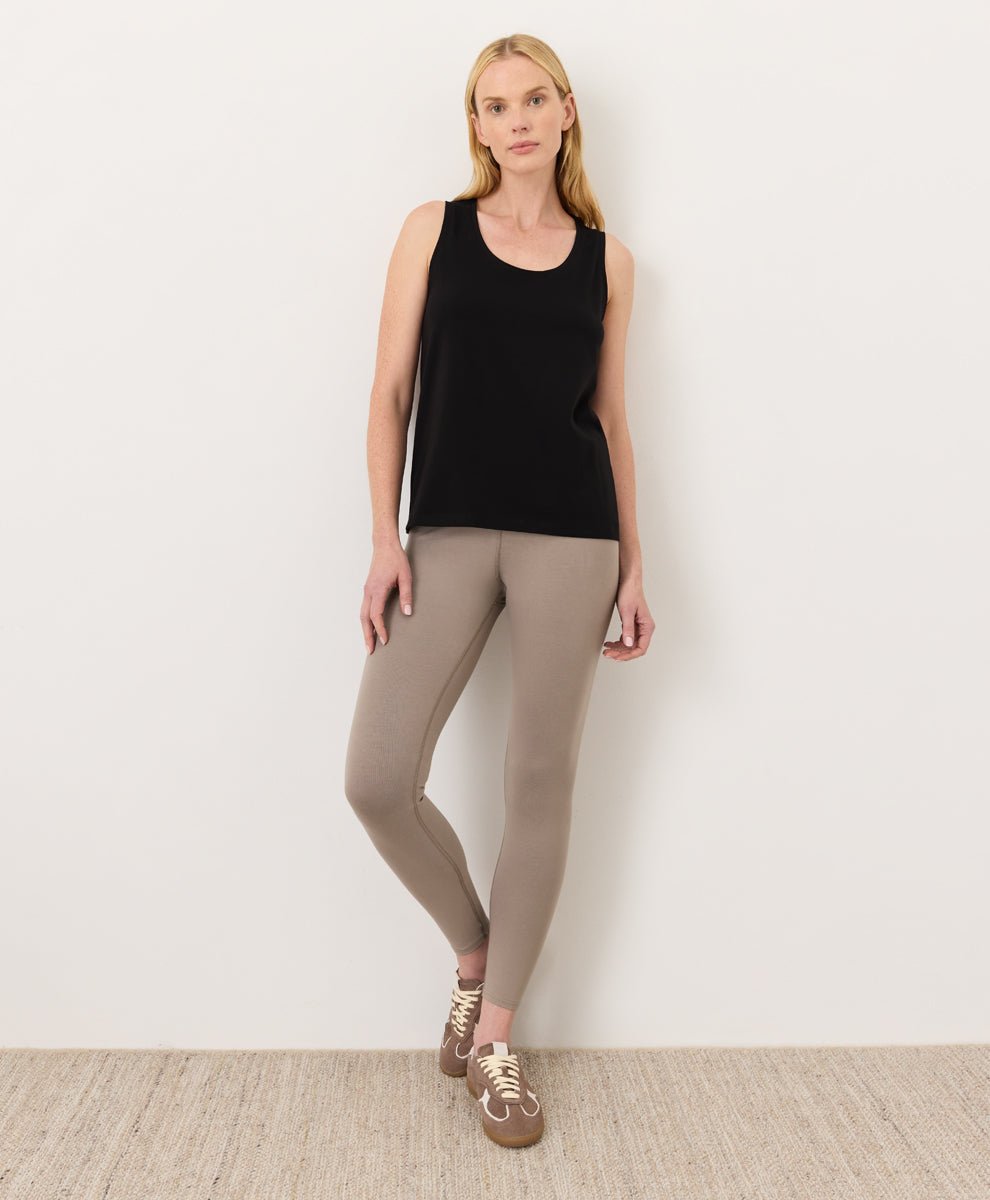 Woman wearing a black Pact Organic Luxe Essential Scoop Neck Tank and cinder leggings against a white background