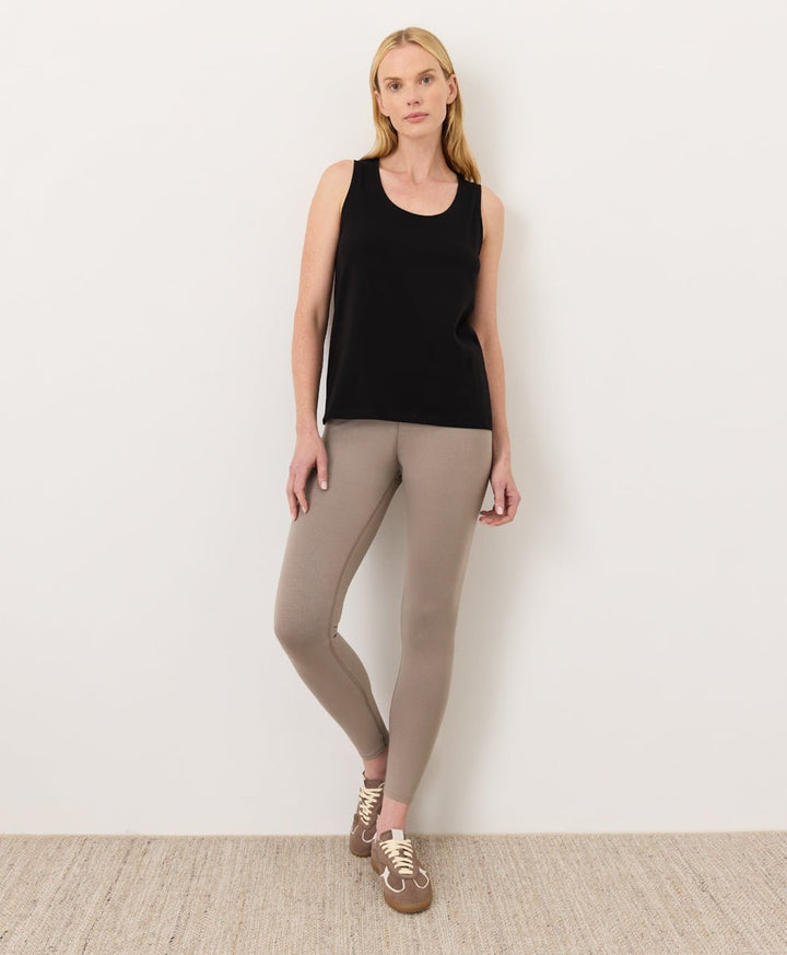 Woman wearing a black Pact Organic Luxe Essential Scoop Neck Tank and cinder leggings against a white background