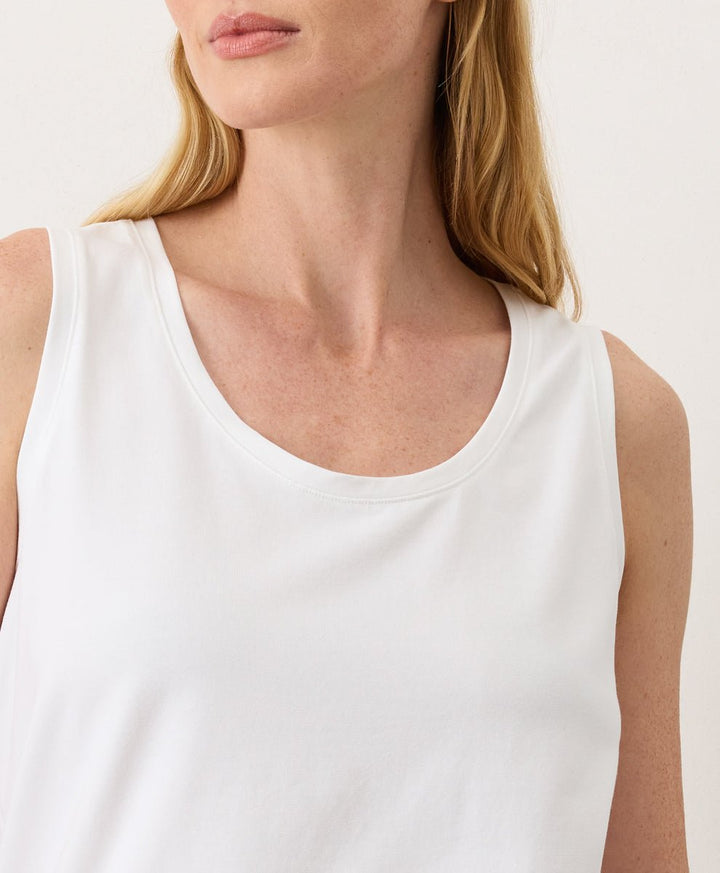 Woman wearing a white Pact Organic Luxe Essential Scoop Neck Tank against a white background