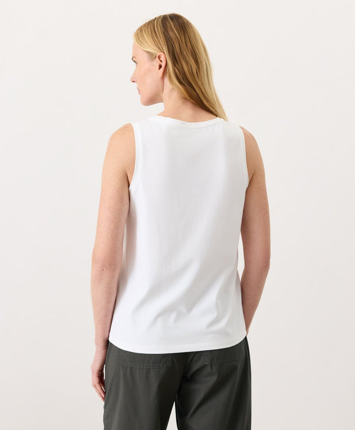 Woman wearing a white Pact Organic Luxe Essential Scoop Neck Tank and dark pants against a white background
