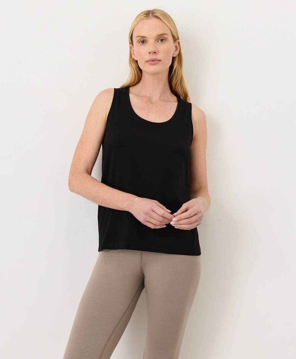 Woman wearing a black Pact Organic Luxe Essential Scoop Neck Tank and cinder leggings against a white background