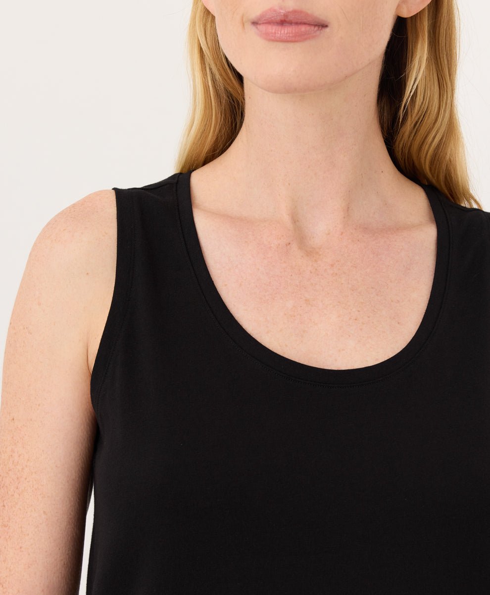 Woman wearing a black Pact Organic Luxe Essential Scoop Neck Tank against a white background