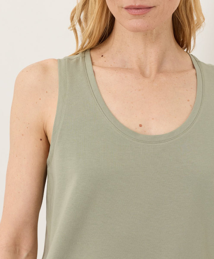 Woman wearing a seagrass Pact Organic Luxe Essential Scoop Neck Tank against a white background