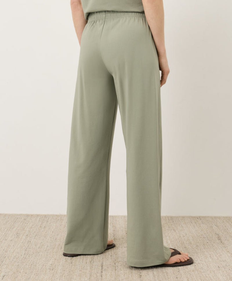Person wearing green wide-leg pants on a neutral background