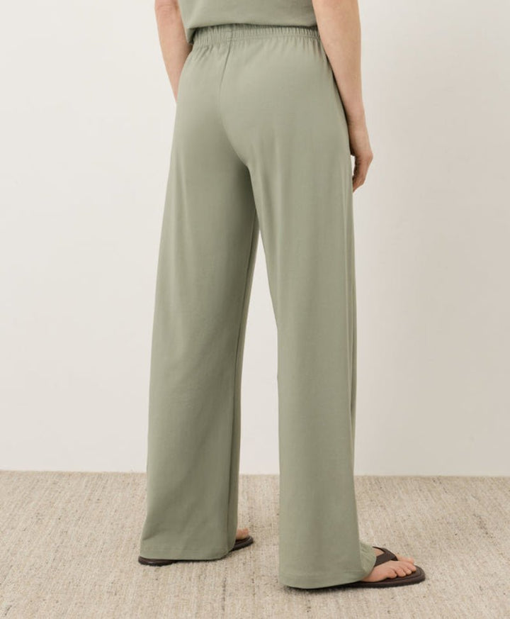 Person wearing green wide-leg pants on a neutral background