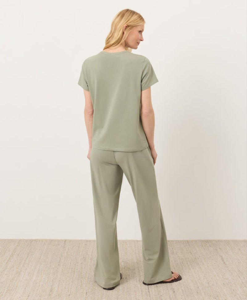 Woman wearing a green outfit standing against a white background