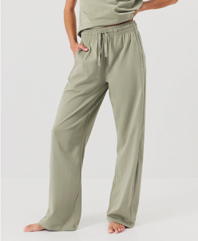 Person wearing olive green lounge pants on a white background