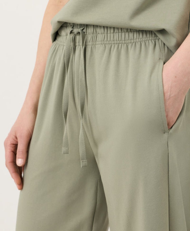Green pants with a drawstring waist on a plain background