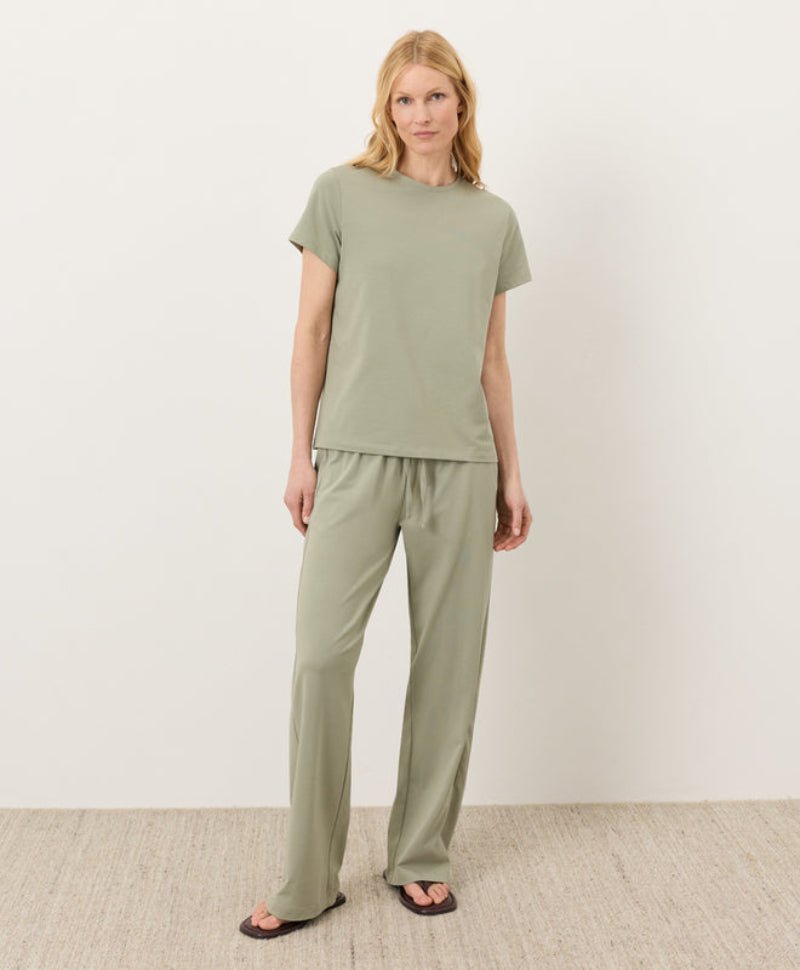 Woman wearing a green outfit standing against a white background