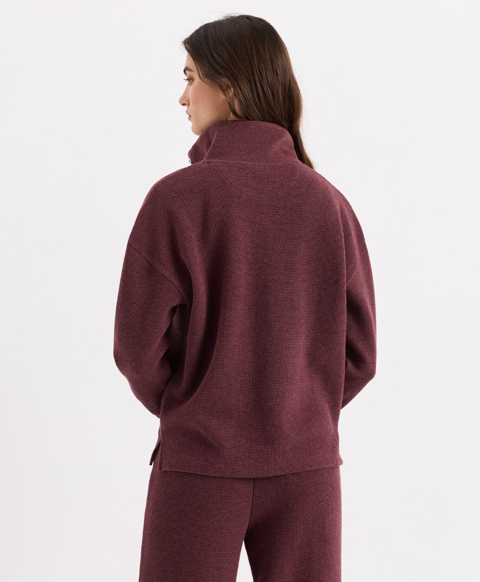 A woman shown from the back wearing a merlot heather henley and matching pants against a clean white studio background.