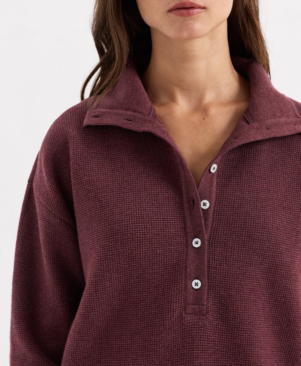 Close-up of a model wearing a textured waffle henley shirt in merlot heather, featuring a collar and white buttons.