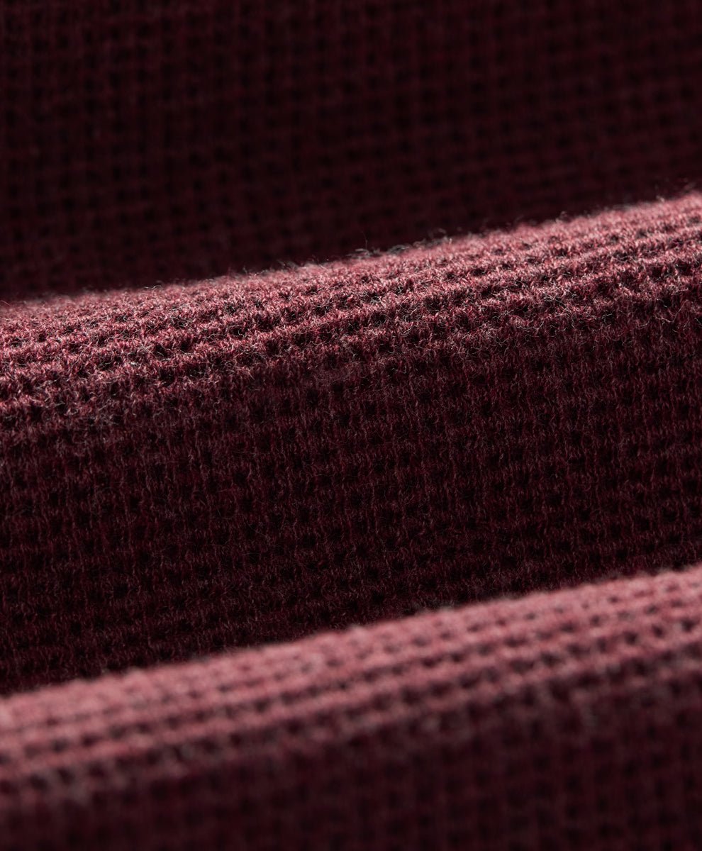 Close-up of a textured waffle fabric in a merlot heather, showing the detailed weave and soft folds.