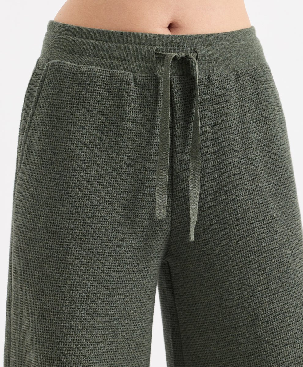 Close-up of a person wearing textured dusted green heather wide-leg pants with a matching drawstring waistband, shown against a plain light background.