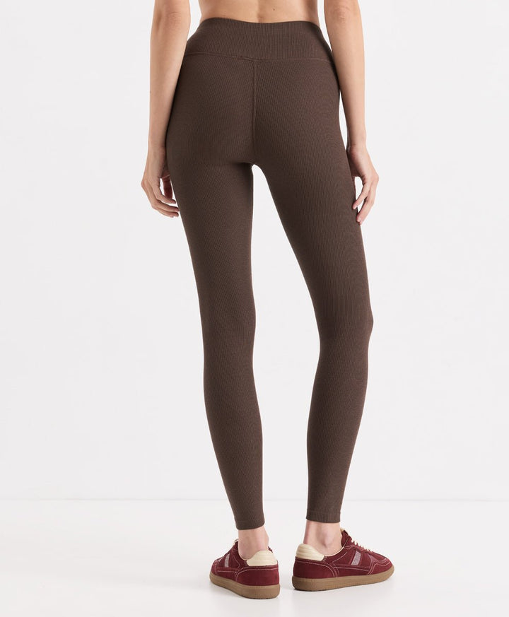 A model from the back wearing cocoa ribbed leggings and burgundy platform sneakers against a clean white studio background.