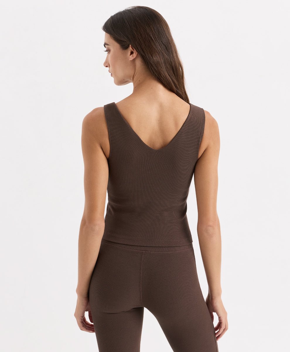 A woman shown from the back wearing a ribbed cocoa sleeveless top and matching leggings against a clean white studio background.