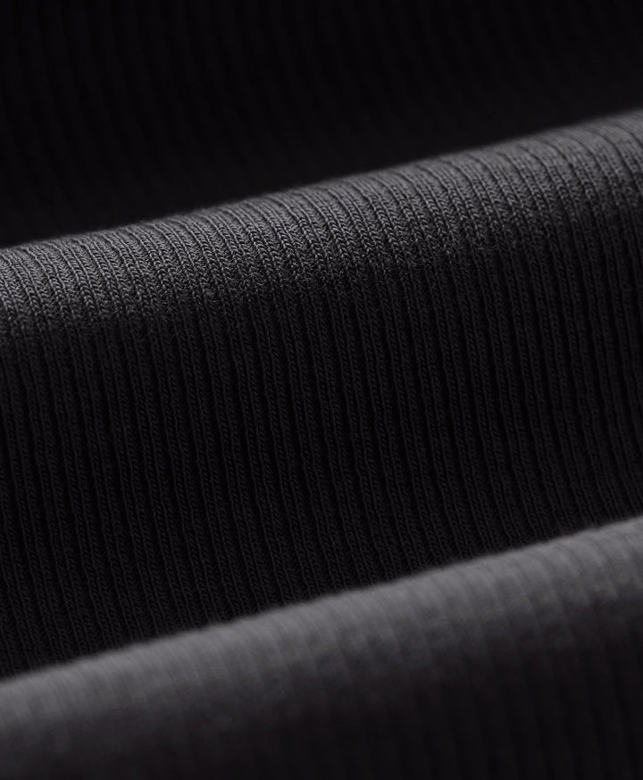 Close-up of a dark ribbed knit fabric with horizontal folds showing the texture and weave.
