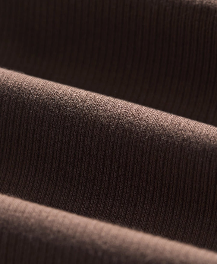 Close-up of a ribbed knit fabric in cocoa, showing the texture and folds.