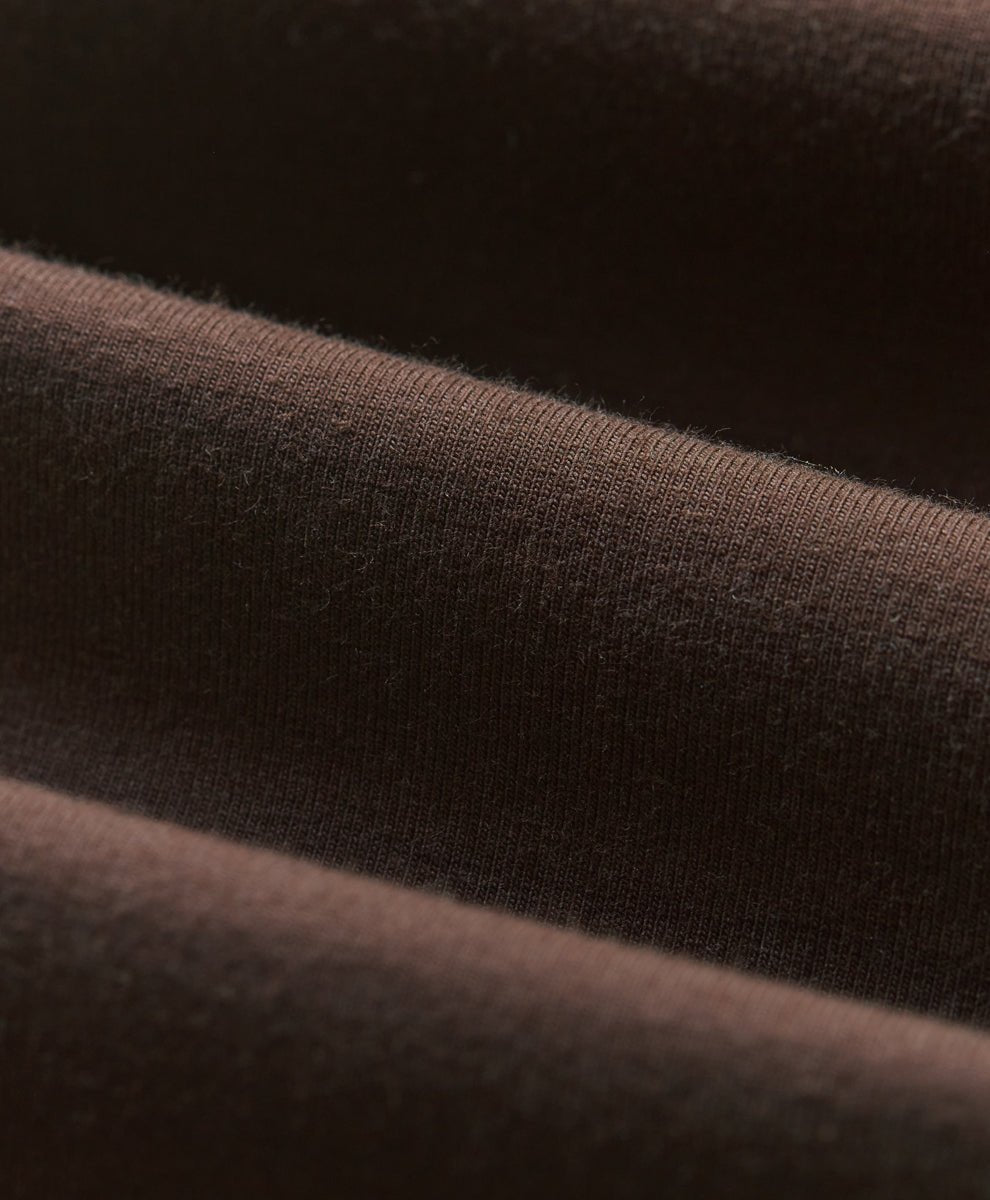 Close-up of cocoa brown knit fabric with soft folds and visible texture.