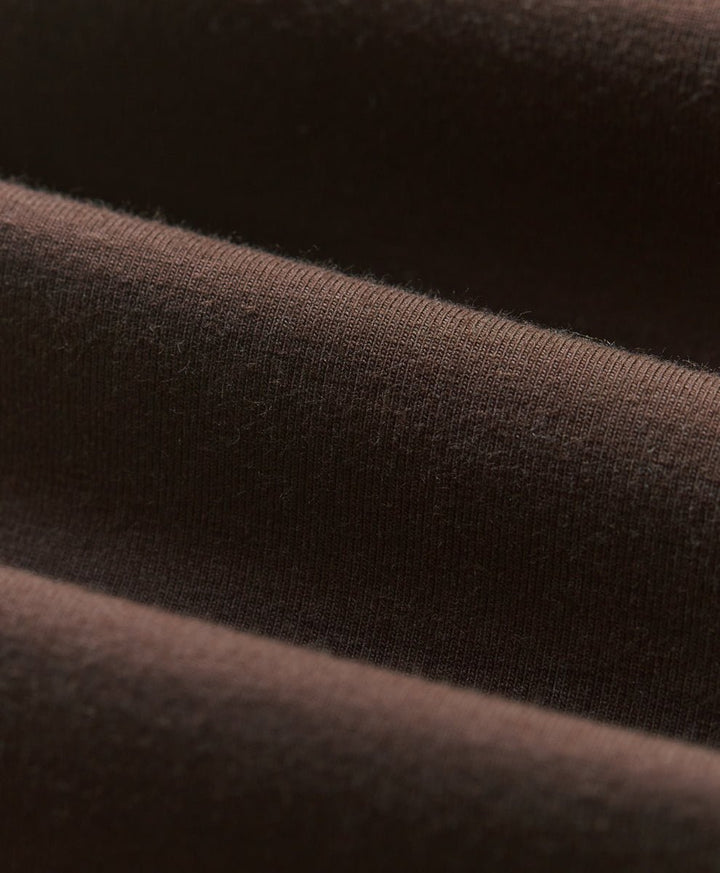 Close-up of cocoa brown knit fabric with soft folds and visible texture.