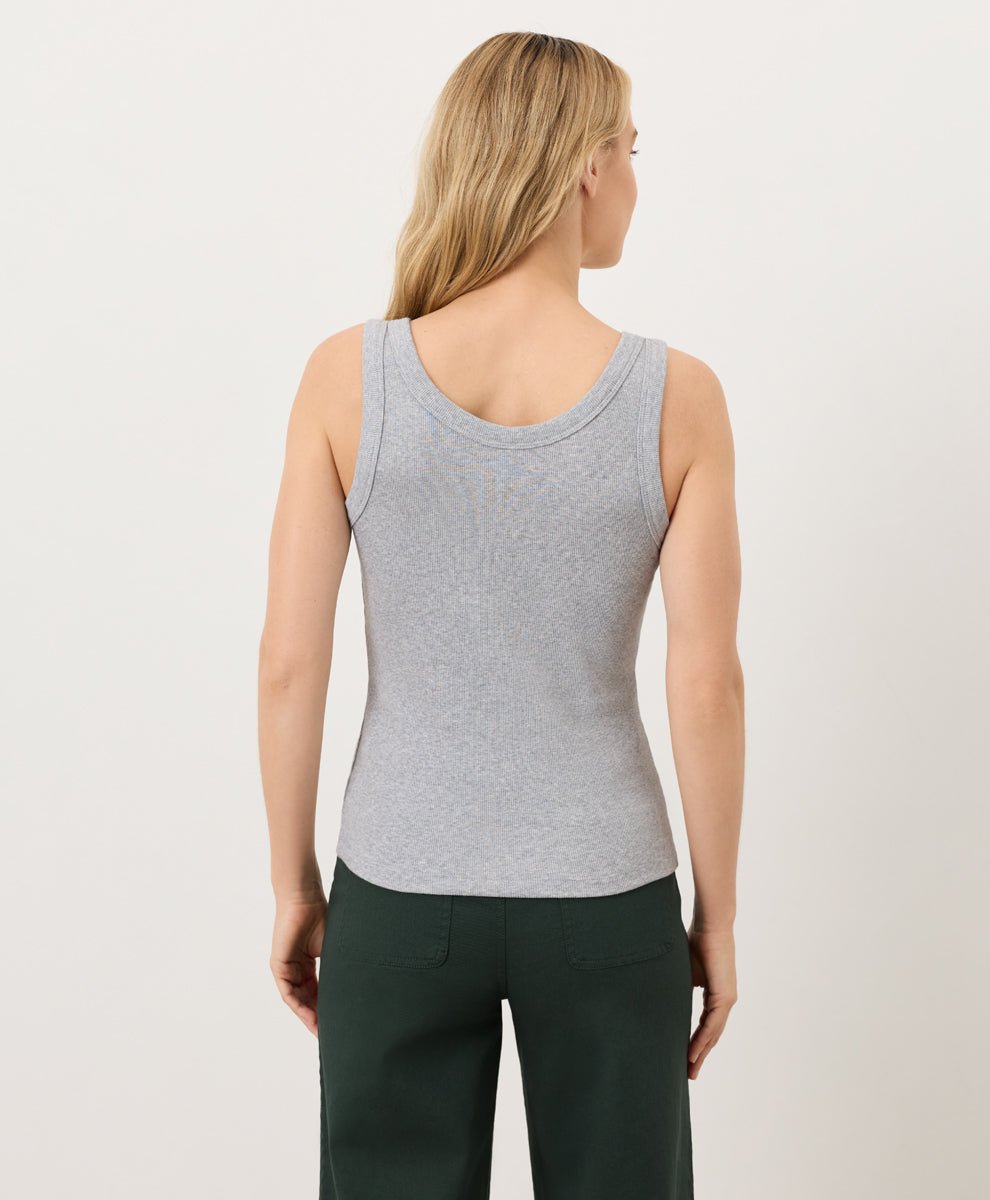 Woman wearing a gray tank top and dark green pants on a light gray background