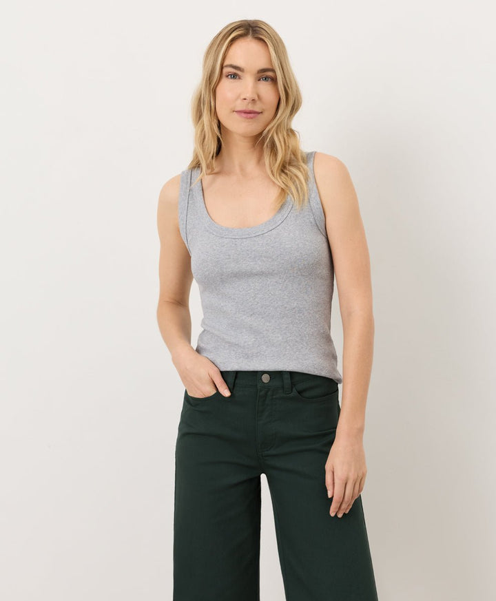 Woman wearing a gray tank top and dark green pants on a white background