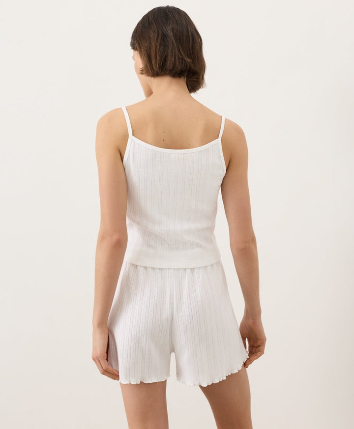 Woman wearing Pact Organic Pointelle Cami and shorts set in white on a white background