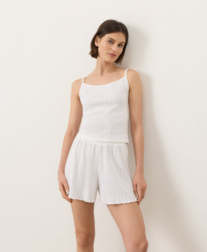 Woman wearing Pact Organic Pointelle Cami and shorts set in white on a white background