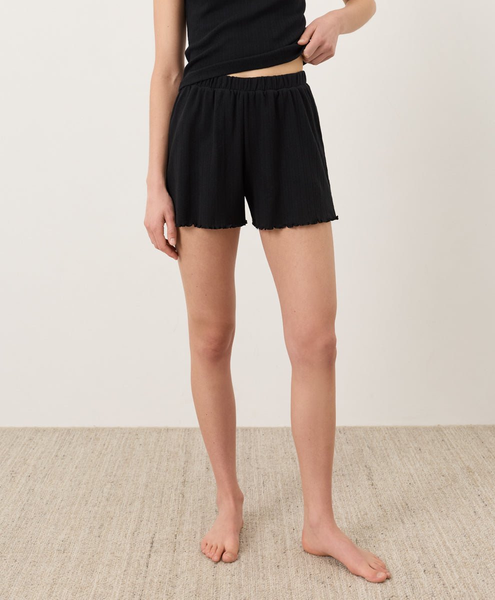 Person wearing black Pact Organic Pointelle Shorts on a plain background