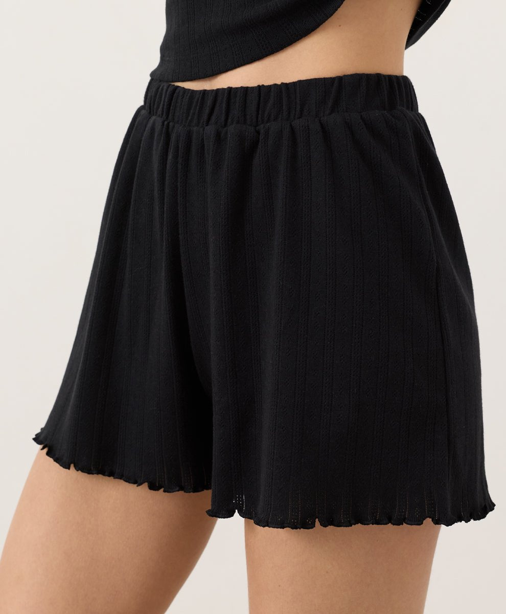 Person wearing black Pact Organic Pointelle Shorts on a plain background