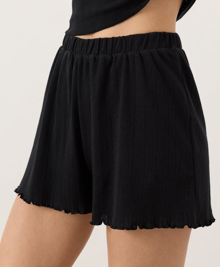 Person wearing black Pact Organic Pointelle Shorts on a plain background