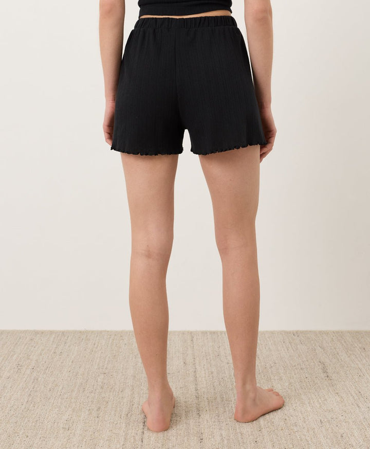 Person wearing black Pact Organic Pointelle Shorts on a plain background