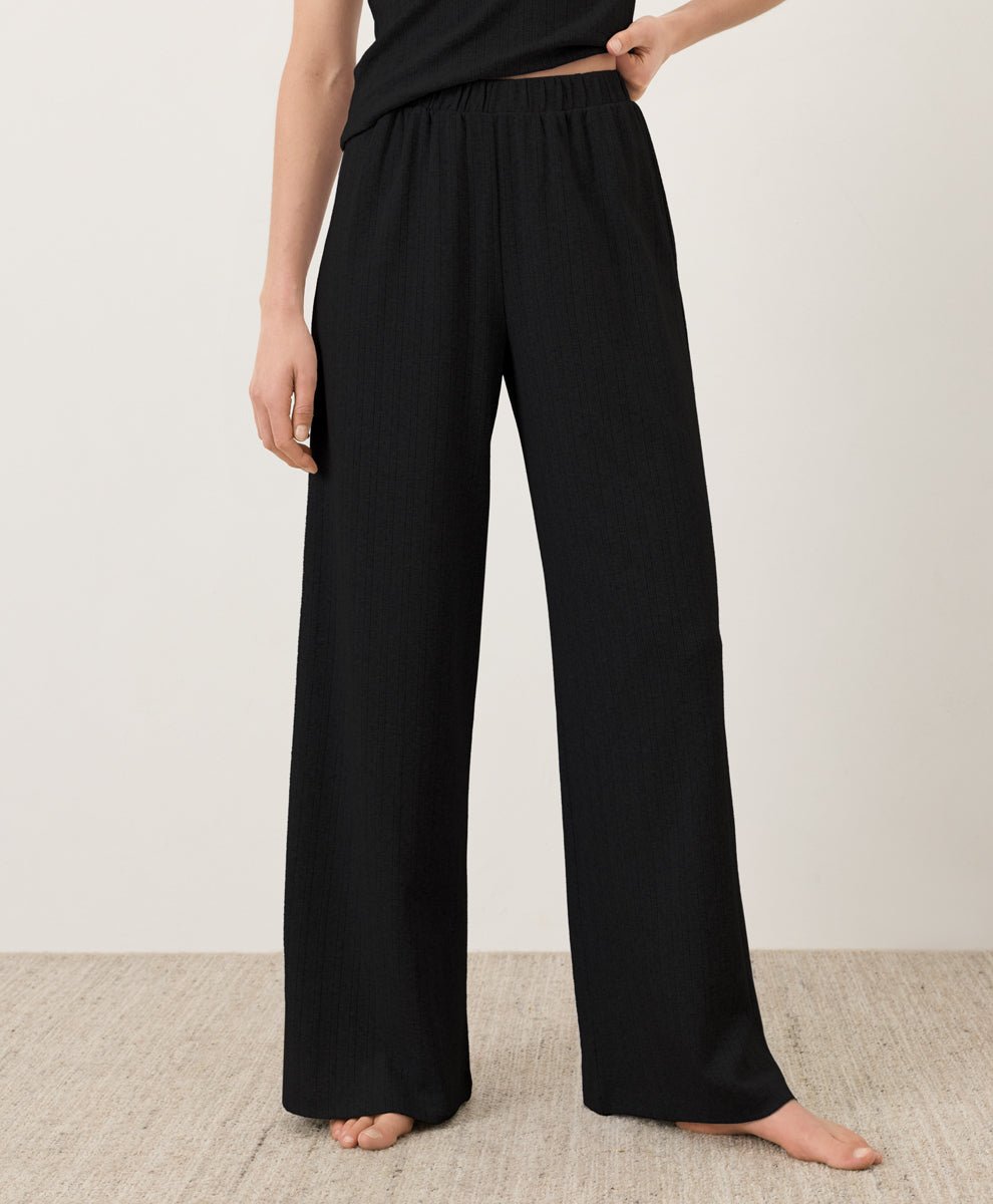 Person wearing Pact's Organic Pointelle Wide Leg Pant in black on a plain background