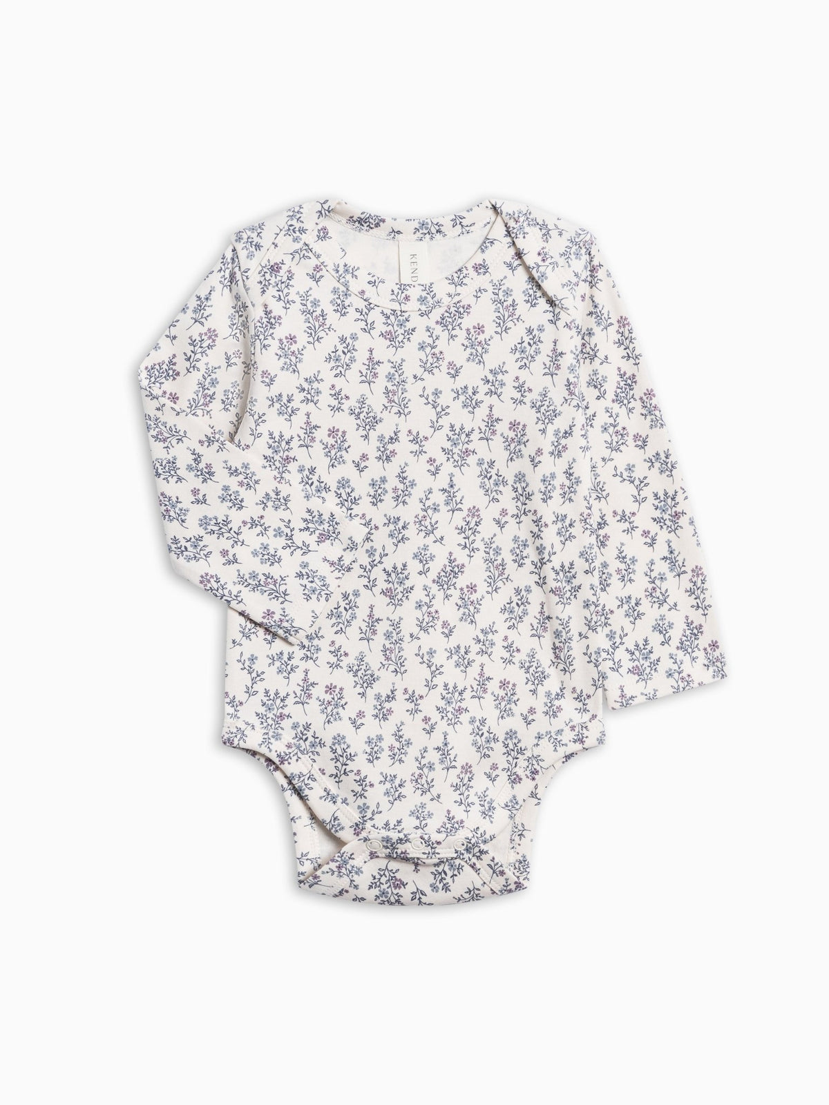 A long-sleeve baby bodysuit with an all-over small floral print in muted blue and purple on a warm off-white background, laid flat against a clean white background.