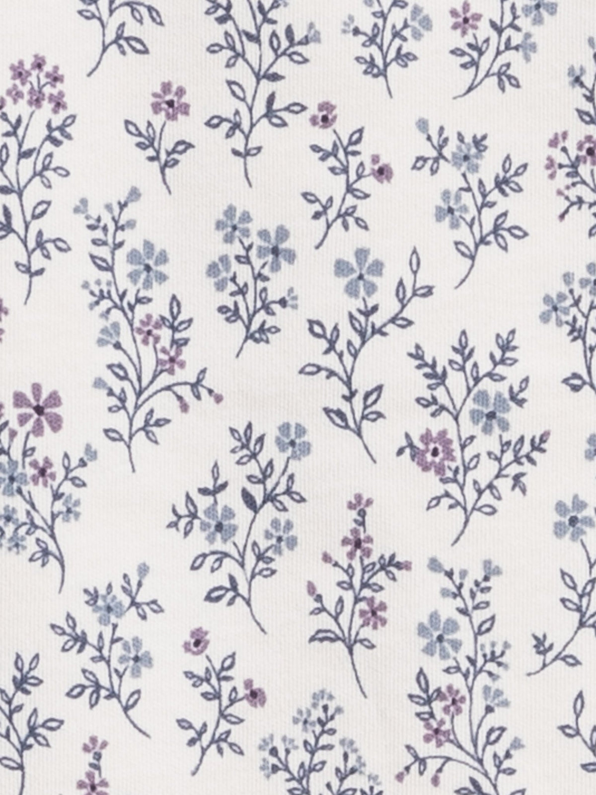A close-up of a white fabric with a delicate repeating floral pattern in muted blue and purple.