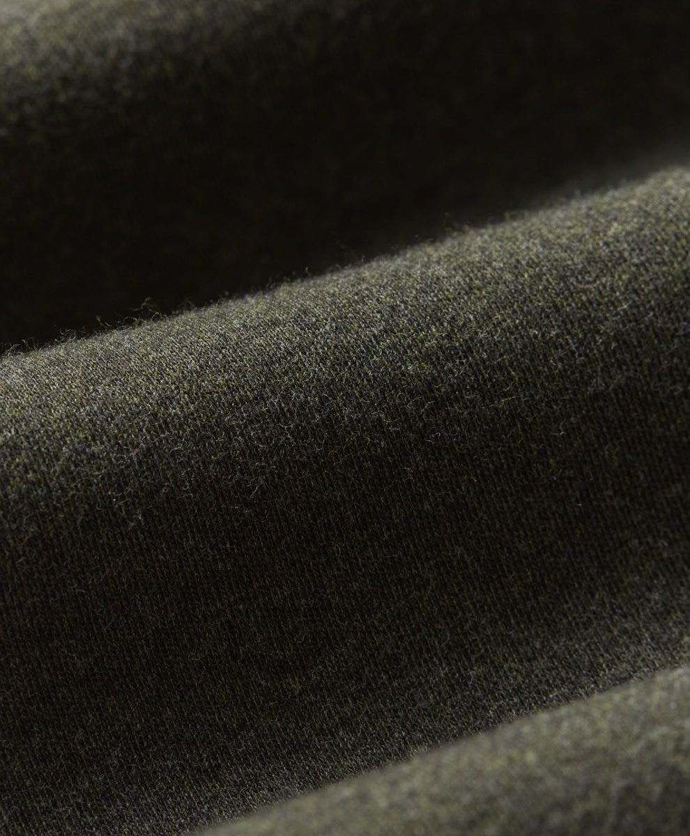 Close-up of loden green fabric with a soft, slightly fuzzy texture and draped folds.