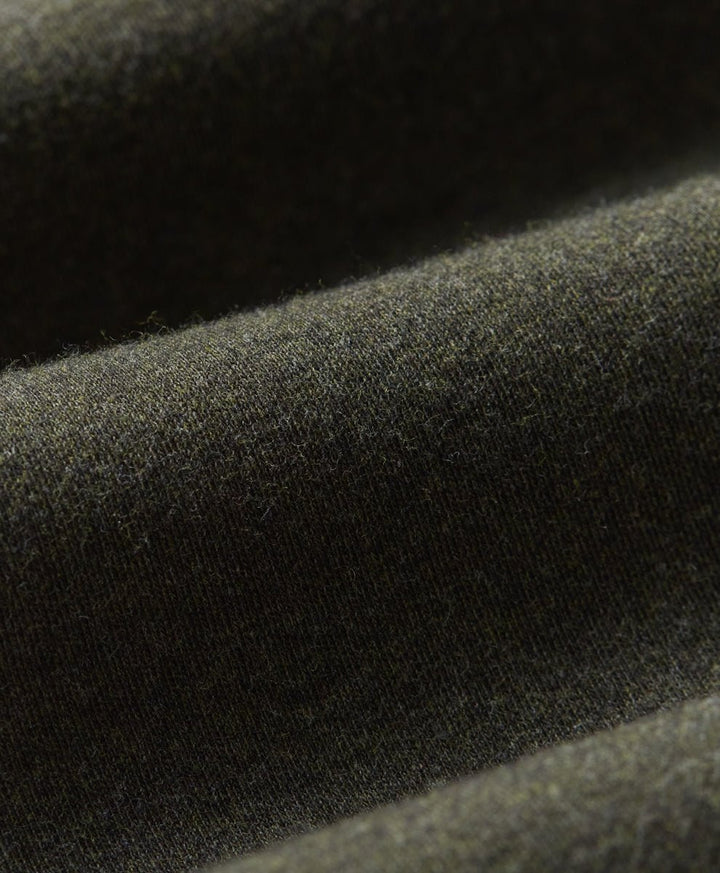 Close-up of loden green fabric with a soft, slightly fuzzy texture and draped folds.
