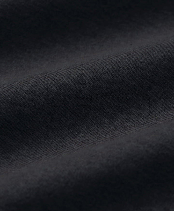 Close-up of dark charcoal heather fabric with soft folds and a fine woven texture.