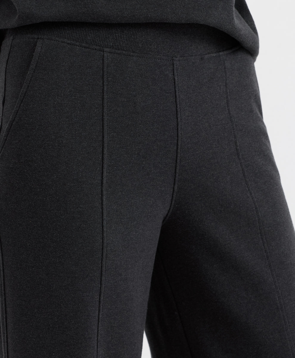 Close-up of dark charcoal heather pants showing the side seam, ribbed waistband, and fabric texture.