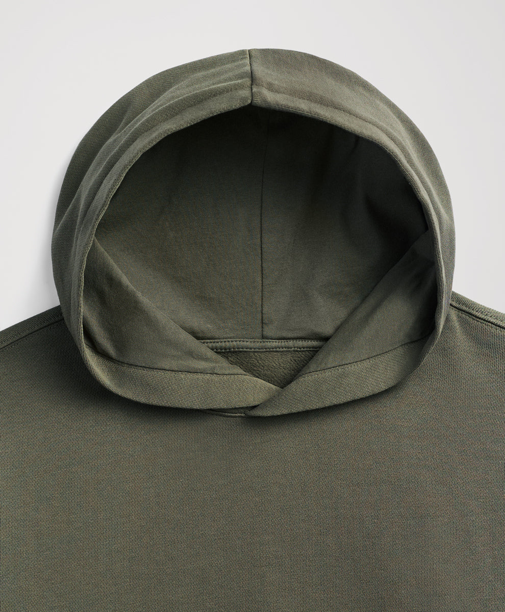 Close-up of the hood and upper chest of a dusted green hoodie against a light gray background.