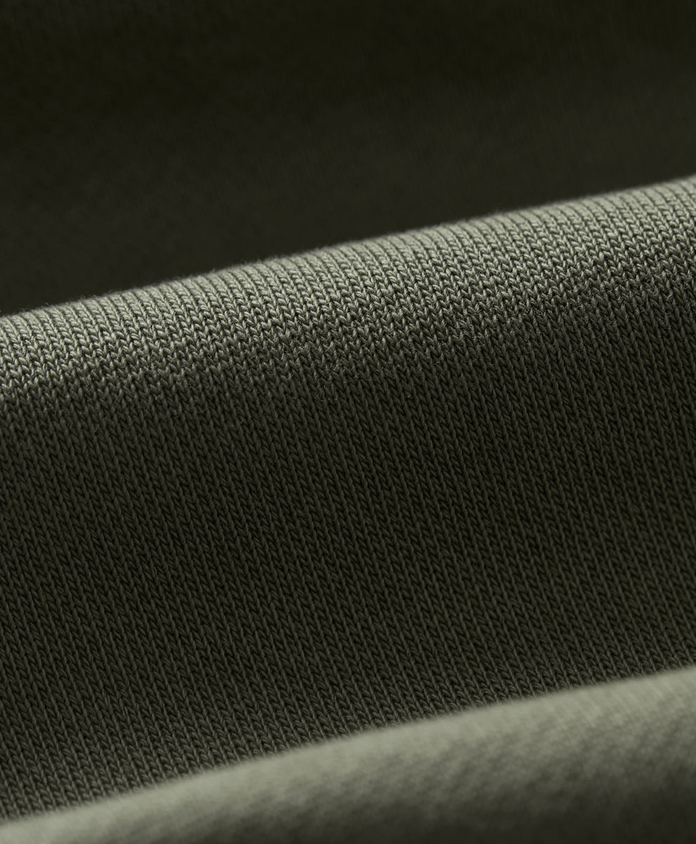 Close-up of a dusted green knit fabric texture with soft folds.
