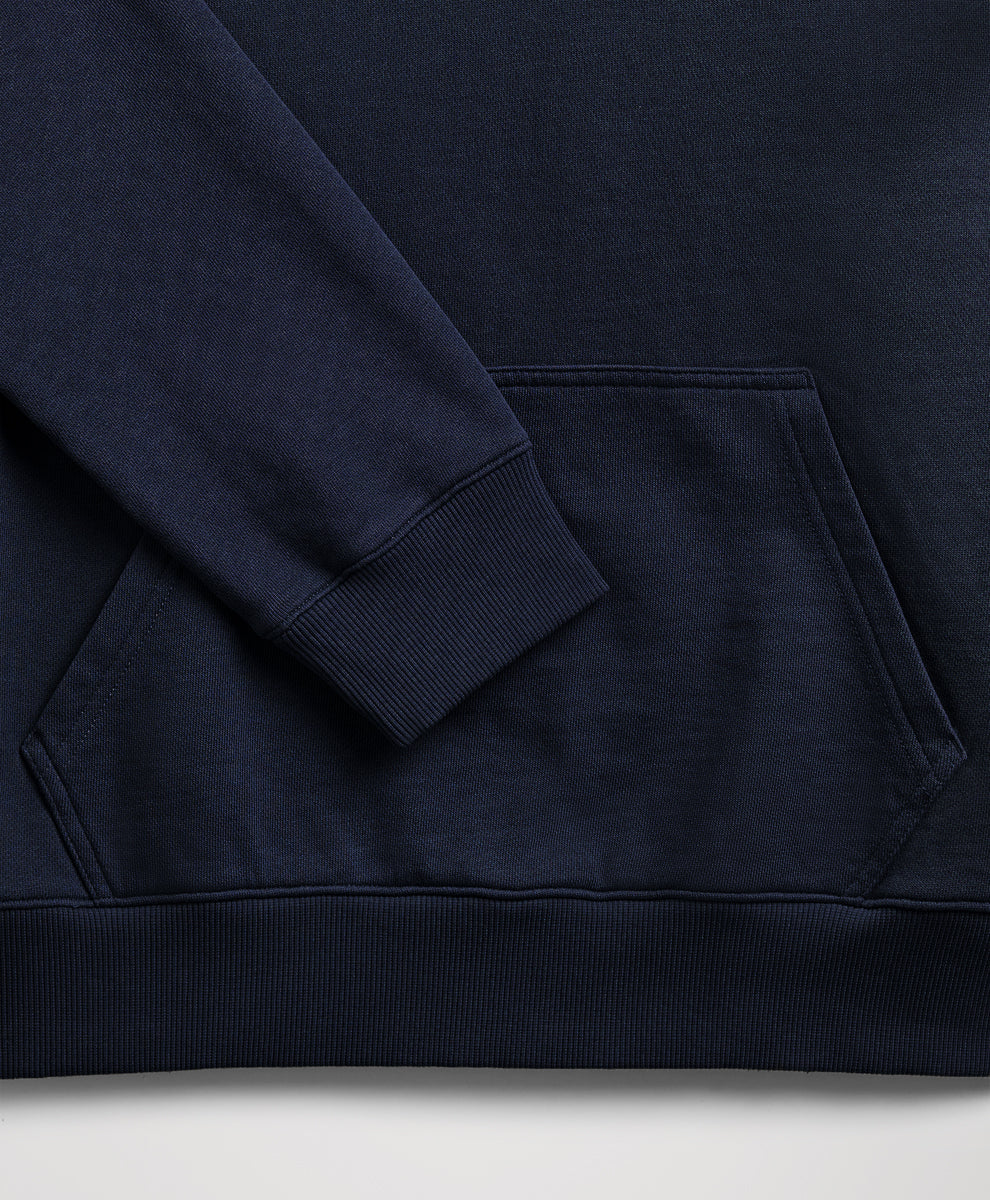 Close-up of a dark navy blue sweatshirt showing the sleeve cuff, ribbed hem, and front kangaroo pocket.