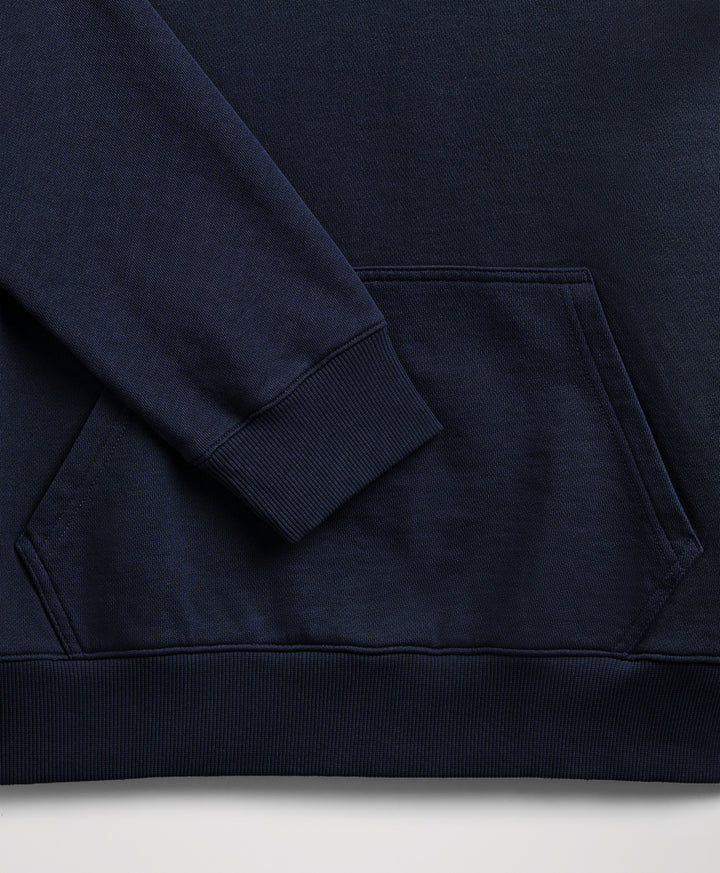 Close-up of a dark navy blue sweatshirt showing the sleeve cuff, ribbed hem, and front kangaroo pocket.