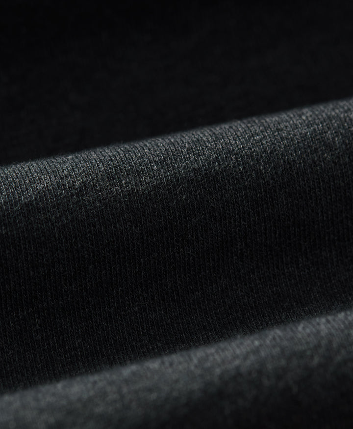 Close-up of a charcoal heather knit fabric with soft folds and a fine textured weave.