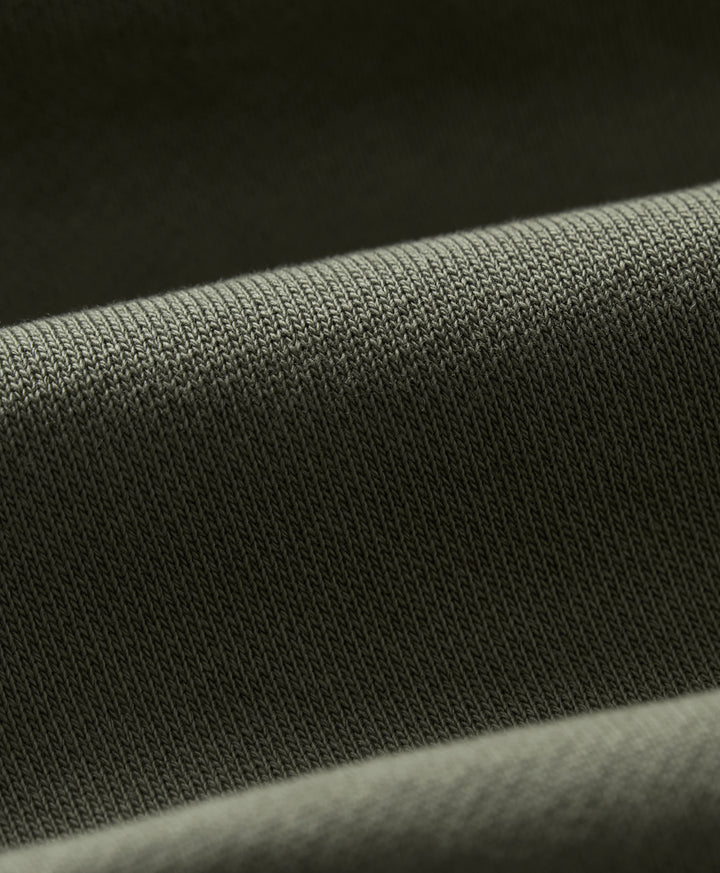 Close-up of a dusted green knit fabric texture with soft folds.